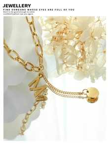 Macro detail of gold letter M pendant and round disc on high-quality titanium steel chain