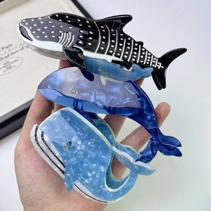Detailed view of three acetate whale hair claws in blue marble and dotted patterns