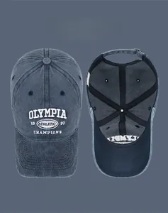Detail of embroidered OLYMPIA lettering on vintage washed denim baseball cap