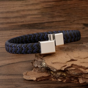 Close-up of woven leather couple bracelet with silver magnetic buckle on wooden bark