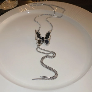 Detail of adjustable silver bolo necklace with black butterfly pendant on a white tray