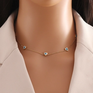 Close-up of golden necklace with heart-shaped evil eye pendants on a female model