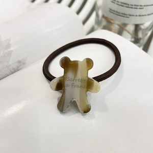 Cute brown hair tie featuring a beige bear cookie charm and Barrette La France text