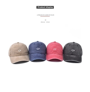 Detail showing four washed cotton baseball caps with embroidered smiley faces in multiple colors