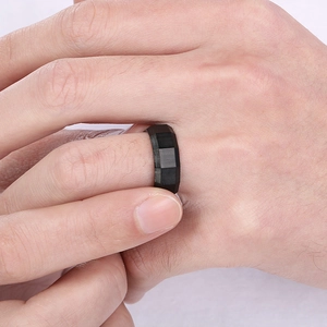 Close-up of a 8mm black brushed faceted stainless steel ring worn on a man's finger