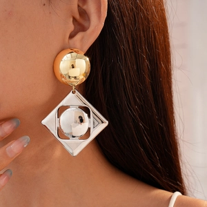 Macro shot of geometric earrings with mixed gold and silver metallic square details