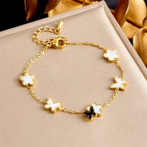 Detail of gold-plated bracelet with white floral charms and a black butterfly charm