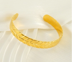 Detailed close-up of golden wheat leaf textured adjustable stainless steel cuff bracelet
