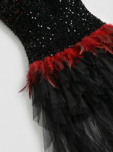 Detail of black sequins and red feather trim on a luxury evening gown with tulle layers