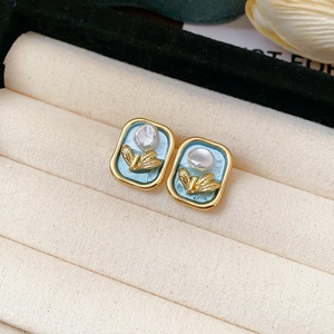Detail showing vintage gold-framed blue enamel earrings with baroque pearl and leaf accent