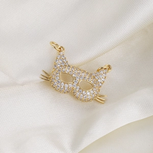 Close-up of golden cat face pendant with pavé-set zircons on soft silk background
