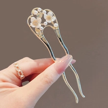 Detailed view of U-shaped gold hair pin featuring delicate pearl flower embellishments