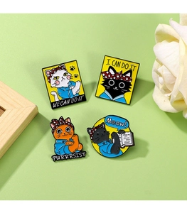 Detailed view of four metal enamel cat badges with motivational text on a flat lay surface