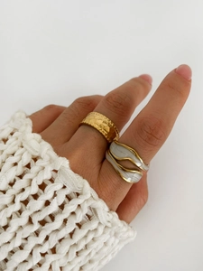 Detail of gold textured rings and white marble inlay worn with a white knit sweater