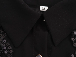 Close-up of black chiffon blouse collar with elegant beadwork and gold-rimmed buttons