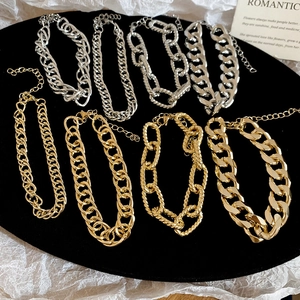 Detail of gold and silver chunky chain bracelets with lobster clasps on a black plate