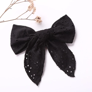 Detail of elegant black Broderie Anglaise bow hair clip with embroidery on white background