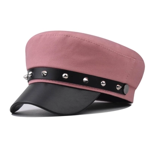 Dettaglio cappello in tela rosa con visiera in pelle nera e borchie metalliche argento