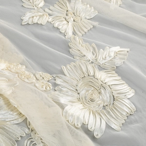 Close-up of white 3D floral ribbon embroidery on delicate mesh lace fabric