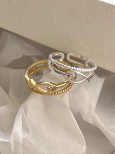 Close-up of gold and silver fish-shaped rings with zircon on white paper