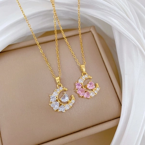 Detail of gold moon pendants with pink and white heart zircons on soft silk fabric