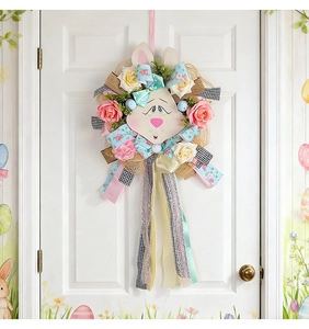 Close-up of Easter wreath with bunny head, pink roses and colorful patterned ribbons on white door
