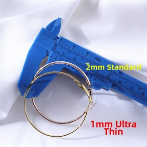 Detail view of 1mm and 2mm hoop earrings compared with a blue measuring caliper