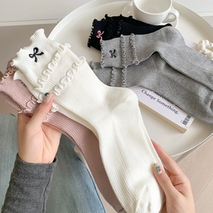 Detail of sweet ballerina style socks with ruffled edges and delicate bow embroidery