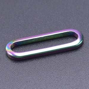 Macro shot of a rainbow-colored oval stainless steel ring accessory with iridescent finish