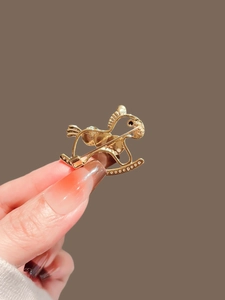 Macro view of a gold-plated rocking horse brooch with white zircon stone inlay