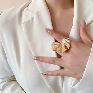 Detail of oversized gold ring featuring abstract wavy textures and artistic metal folds