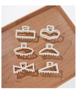 Flat lay of six assorted pearl hair claw clips in geometric shapes on a wooden tray