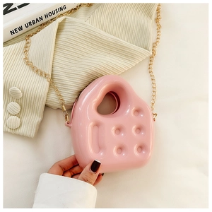Detail of pink jelly handbag with a golden chain strap held against a neutral background