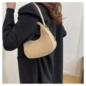 Detail of beige crocodile pattern handbag on model in a stylish black blazer