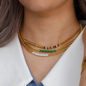Gros plan de colliers multicouches dorés avec des pendentifs en zircone carrés colorés