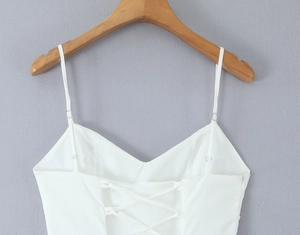 Détail du dos d'une robe blanche avec laçage croisé ajustable et fermeture éclair invisible