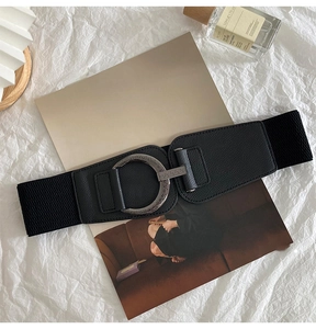 Detail of wide elastic waist belt with vintage silver ring buckle and black leather texture