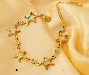 Macro detail of 18K gold starfish bracelet with iridescent shell inlay and zircon