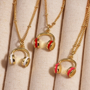 Colorful drip oil headphone pendants on gold beaded chains over a beige fabric background