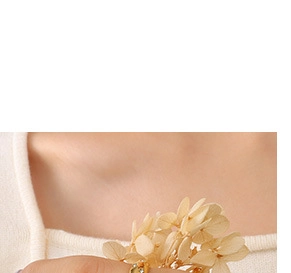 Macro shot of gold flower ring with green gemstones on model holding dry flowers