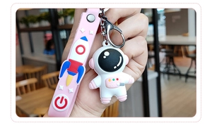 Gros plan d'un porte-clés astronaute en silicone avec une dragonne rose à motif fusée