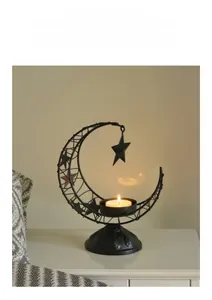Macro detail of crescent moon iron candle holder with star pendant and lit tea light