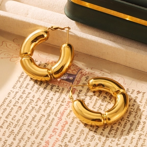 Chunky gold hollow bamboo C-shaped titanium steel hoop earrings on a vintage paper