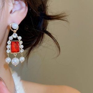 Vue macro de boucles d'oreilles vintage avec pierre rouge et perles blanches pendantes