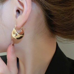Close-up of chunky gold hoop earrings with a high-polished mirror finish on model