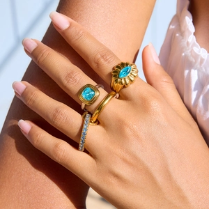 Stackable gold-plated stainless steel rings featuring light blue cubic zirconia stones