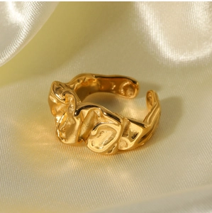 Close-up of golden irregular lava texture on an adjustable open ring over beige silk