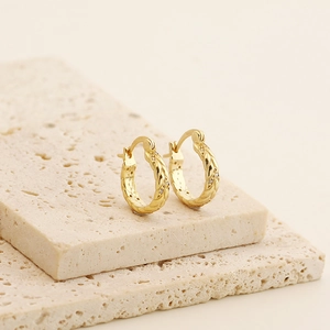 Macro shot of gold hoop earrings with braided texture and shimmering pavé stones