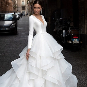 Detailed view of layered ruffle skirt and long sleeves on a white deep V-neck wedding gown