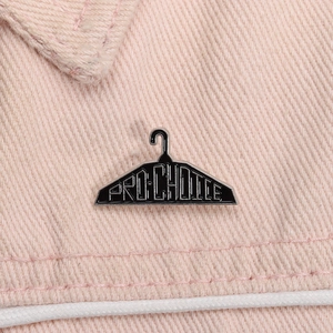 Pro-Choice enamel coat hanger brooch badge in black and white on pink denim jacket